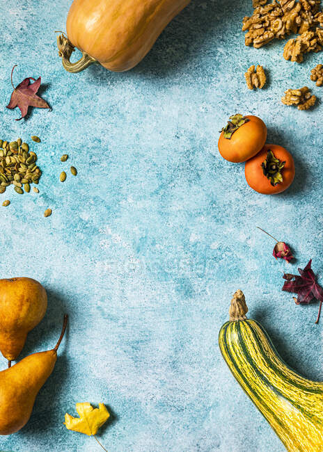 Autumnal background with pumpkins, fallen leaves, pears, walnuts, pumpkin seeds, persimmons and copy space — Stock Photo