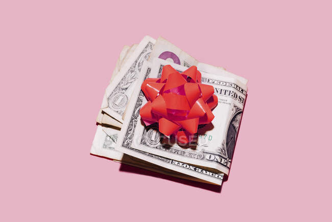 Studioaufnahme gefalteter Dollarscheine mit roter Schleife — Stockfoto