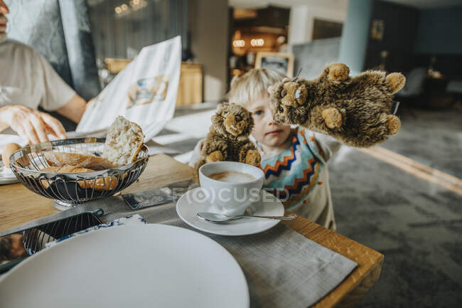 Хлопчик, який показує іграшку альпійського Мармота за столом у готельному номері. — стокове фото