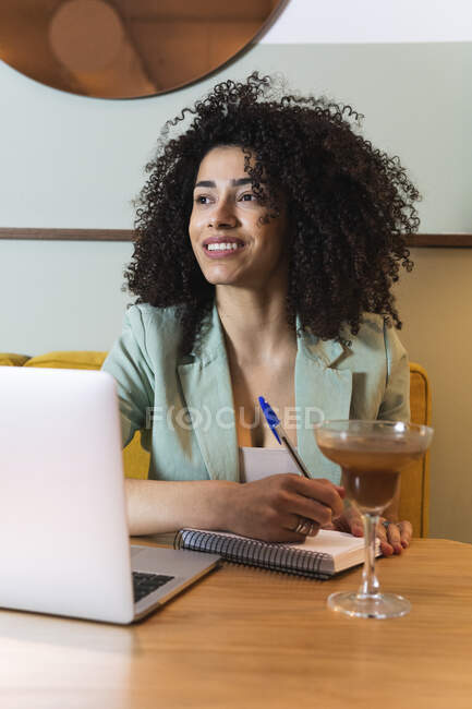 Nachdenkliche Geschäftsfrau mit Buch und Laptop schaut im Restaurant weg — Stockfoto