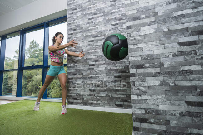 Deportiva haciendo ejercicio con balón de medicina en el gimnasio - foto de stock