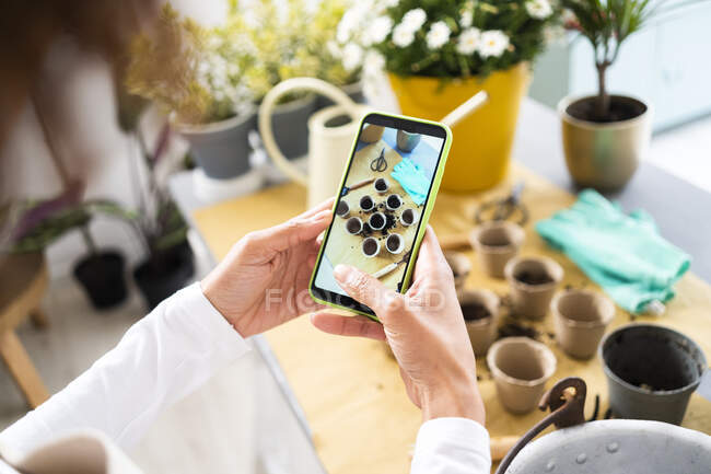 Floristin fotografiert Blumentöpfe per Handy im Pflanzenladen — Stockfoto