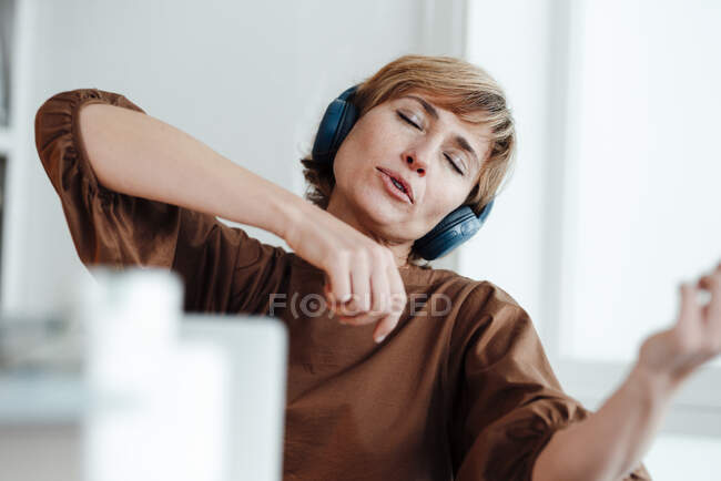 Donna d'affari sognare ad occhi aperti durante l'ascolto di musica attraverso le cuffie in ufficio — Foto stock