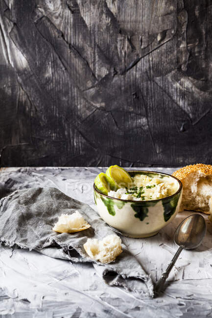 Bowl of Greek avgolemono soup with rice, lemon slices and bread — Stock Photo
