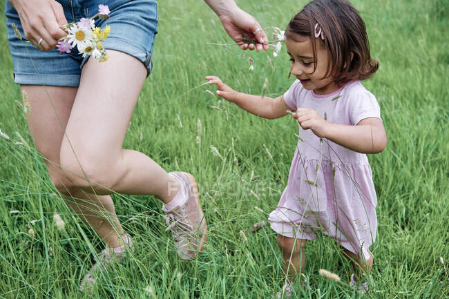 Donna con fiori che cammina con figlia sull'erba nel parco — Foto stock