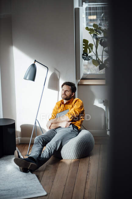 Empresário com tablet digital sentado em hassock no escritório — Fotografia de Stock