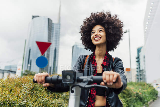 Happy woman riding electric push scooter in city — Stock Photo