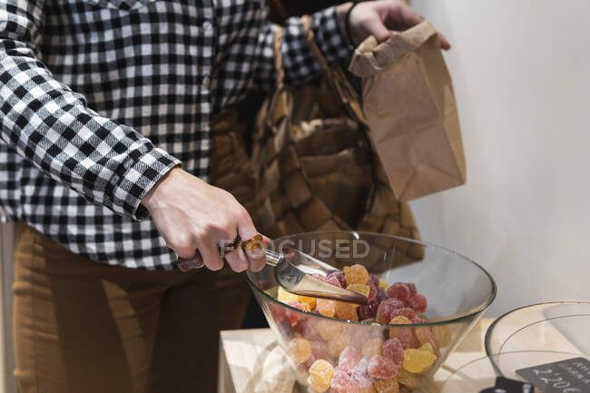 Woman picking candies from glass bowl at supermarket — Stock Photo