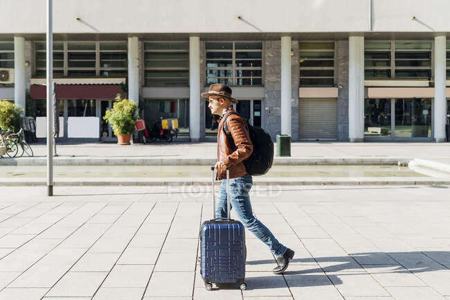 Человек с багажом ходит по тропинке в солнечный день — стоковое фото