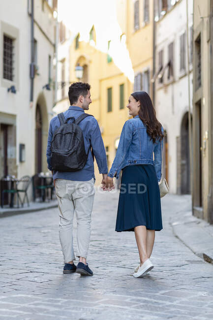 Tourist couple holding hands while walking on footpath — Stock Photo
