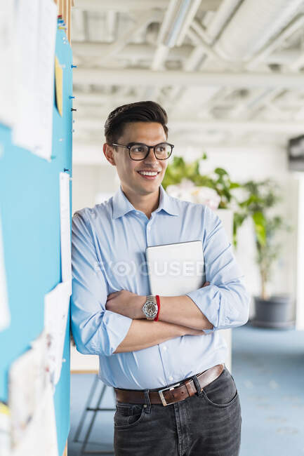 Thoughtful businessman with arms crossed standing in office — Stock Photo