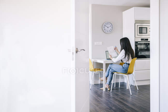 Mujer leyendo papel mientras está sentado en casa oficina - foto de stock