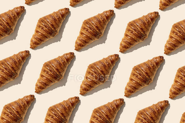 Frisch gebackene Buttercroissants auf beigem Hintergrund — Stockfoto