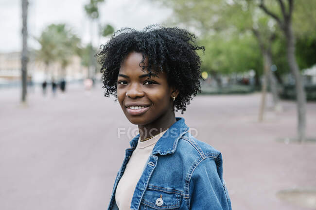Mujer joven sonriente con peinado afro en la ciudad - foto de stock