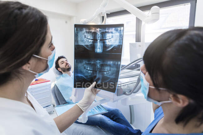Une dentiste montre une radiographie à une assistante à la clinique — Photo de stock