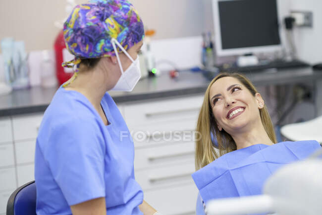 Sorridente paziente femminile che parla con il dentista in clinica — Foto stock