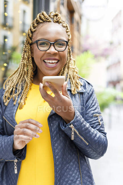Щаслива жінка з косами розмовляє через диктора на смартфоні — стокове фото