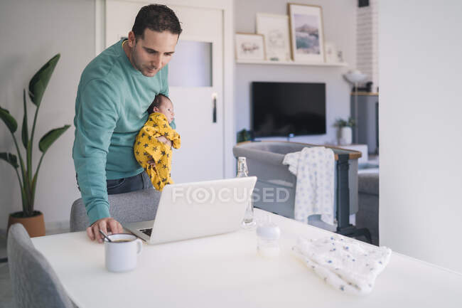 Père portant fils tout en regardant ordinateur portable dans le bureau à la maison — Photo de stock