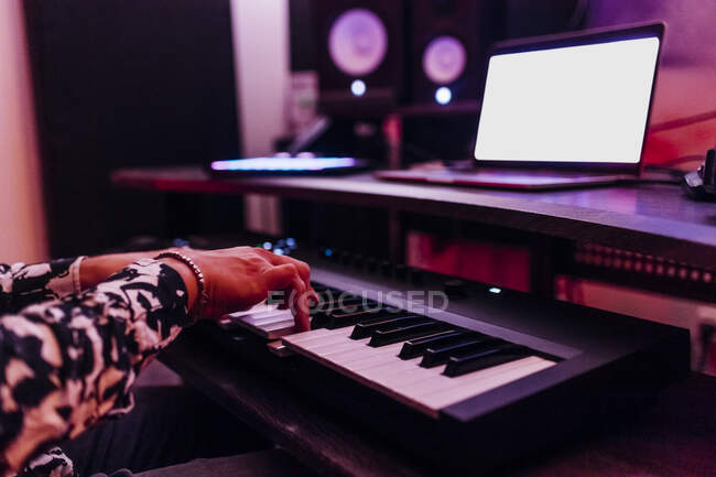 Молодий чоловічий композитор грає на фортепіано перед ноутбуком у студії. — стокове фото
