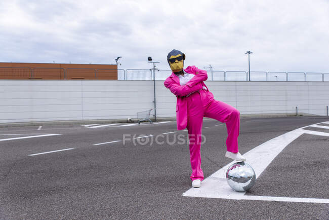 Забавный персонаж в маске животного и розовом деловом костюме веселится на пустой парковке — стоковое фото