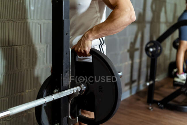 Uomo che organizza il disco del bilanciere in palestra — Foto stock