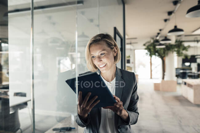 Усміхаючись бізнес-леді за допомогою цифрових планшетного ПК в офісі — стокове фото
