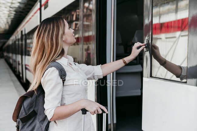 Jovem passageira pressionando botão no trem na estação ferroviária — Fotografia de Stock
