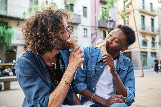 Gay couple eating ice cream while looking at each other — Stock Photo