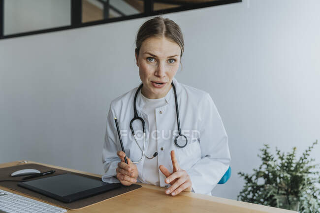 Femme médecin discutant tout en étant assis au bureau — Photo de stock