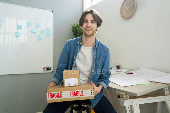 Чоловік - підприємець тримає тендітну коробку під час роботи. — стокове фото
