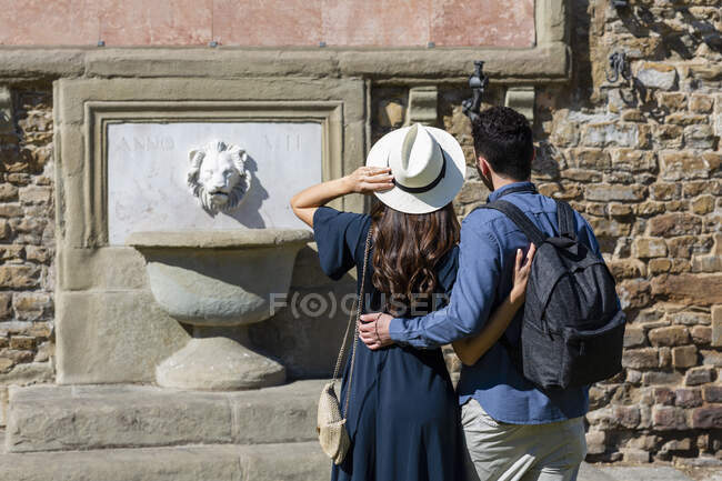 Tourist couple looking at fountain during sunny day — Stock Photo