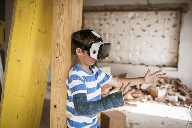 Мальчик с наушниками виртуальной реальности протягивает руку во время ремонта чердака — стоковое фото