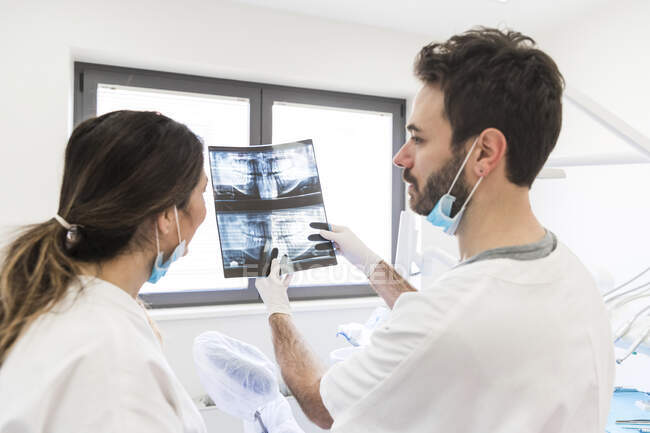 Male dentist showing x-ray to female assistant at medical clinic — Stock Photo