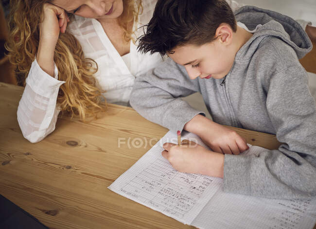 Fils apprendre avec la mère tout en étudiant à la maison — Photo de stock