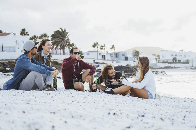 Freunde unterhalten sich beim Trinken am Strand — Stockfoto