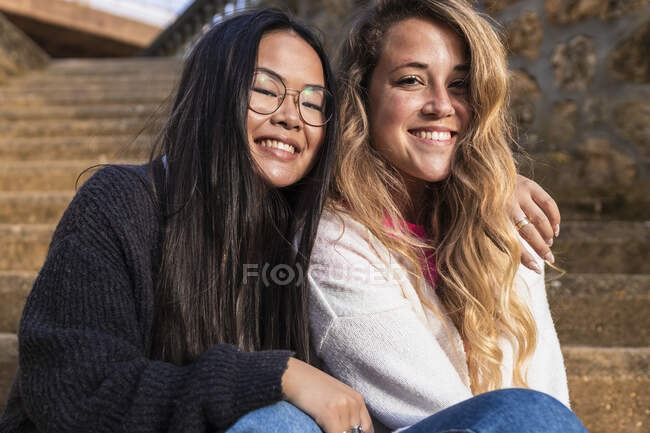 Sorridente amiche donne sedute su gradini — Foto stock