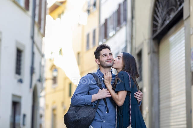 Femme touriste baisers homme tandis que debout sur la rue de la ville — Photo de stock