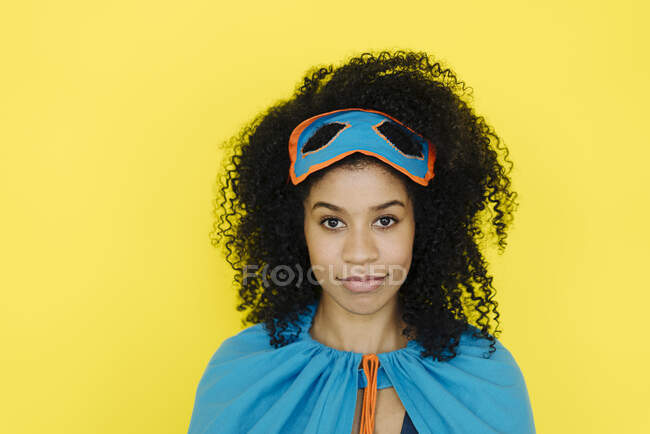 Afro mujer vistiendo traje de superhéroe de pie sobre fondo amarillo - foto de stock