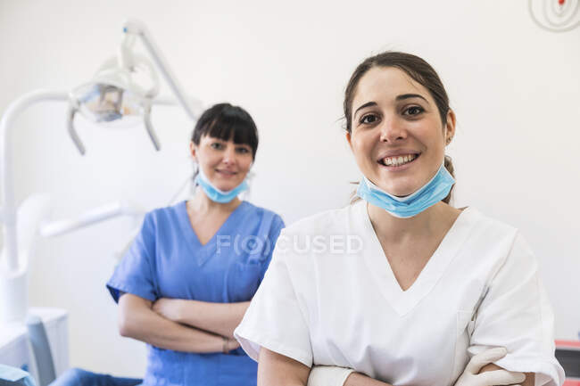 Улыбающиеся женщины-дантисты со скрещенными руками в медицинской клинике — стоковое фото