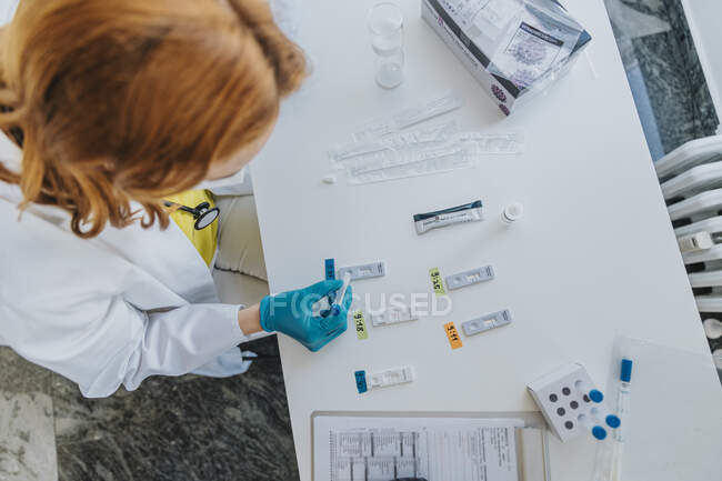 Женщина-врач общей практики делает медицинский образец быстрого диагностического теста в смотровой комнате — стоковое фото
