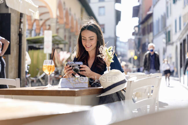 Donna sorridente controllo fotocamera al caffè marciapiede — Foto stock