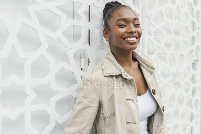 Donna sorridente in piedi davanti al muro bianco — Foto stock