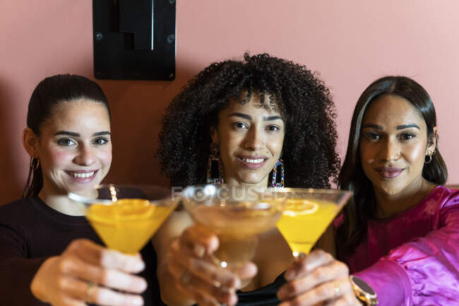 Smiling female friends toasting drinks in restaurant — Stock Photo