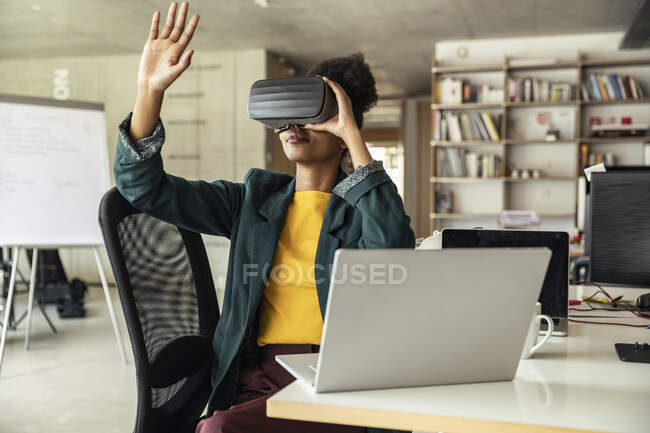 Businesswoman wearing virtual reality simulator gesturing at desk in office — Stock Photo