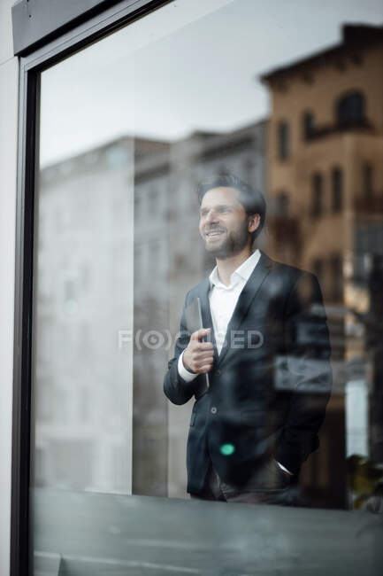 Homme d'affaires avec poches à la main regardant par la fenêtre au bureau — Photo de stock