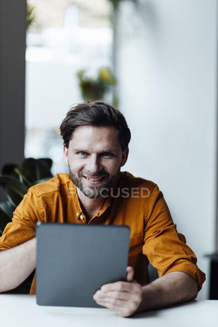 Homme entrepreneur avec tablette numérique souriant dans le bureau — Photo de stock