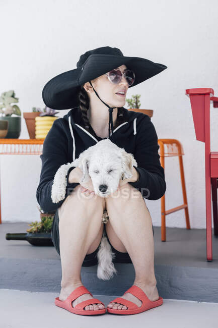 Взрослая женщина с собакой, размышляющая, сидя в патио — стоковое фото
