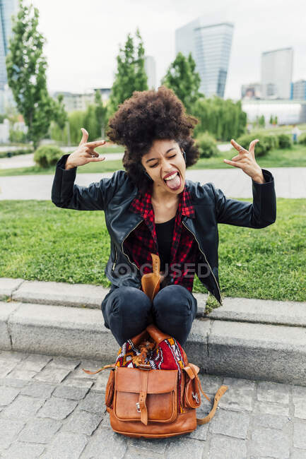 Giovane donna gesturing corno segno mentre attaccare fuori lingua — Foto stock