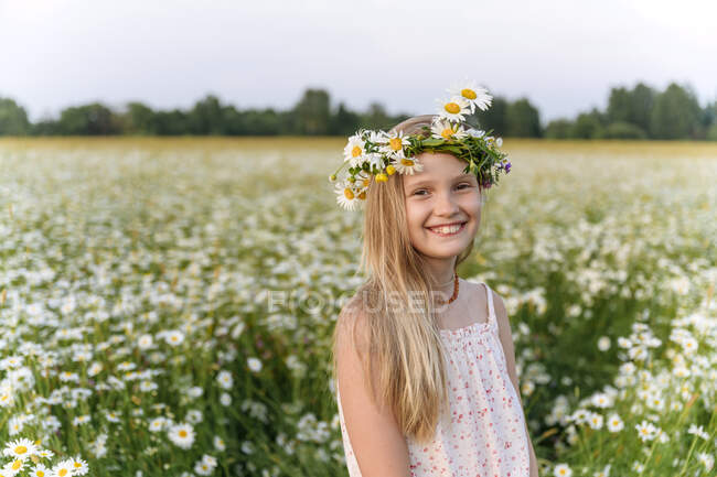 Menina com tiara camomila sorrindo enquanto estava em campo — Fotografia de Stock