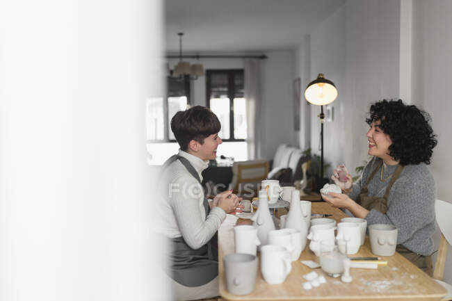 Female artists talking while working on craft product at workshop — Stock Photo